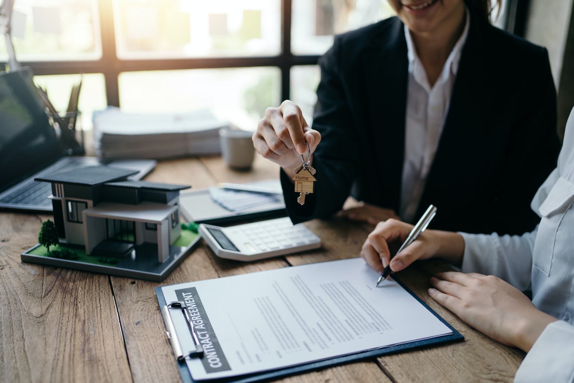 Signing a home loan purchase agreement with a real estate agent.